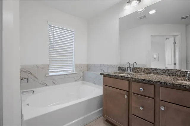 a bathroom with a granite countertop sink and a bathtub