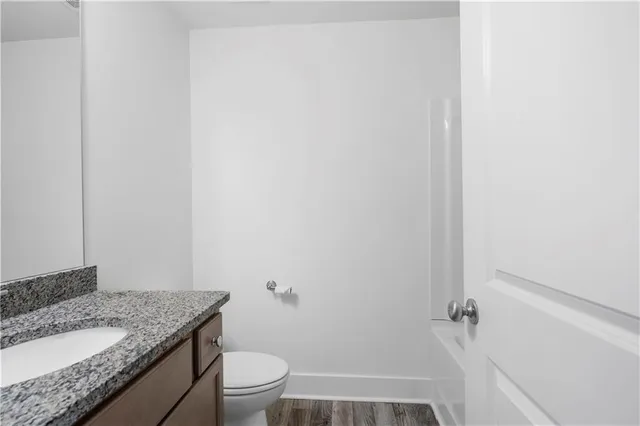 a bathroom with a granite countertop sink toilet and a mirror