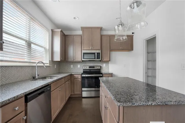 a kitchen with stainless steel appliances granite countertop a sink dishwasher a stove and a refrigerator