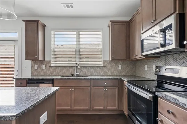 a kitchen with stainless steel appliances granite countertop a sink a stove and cabinets