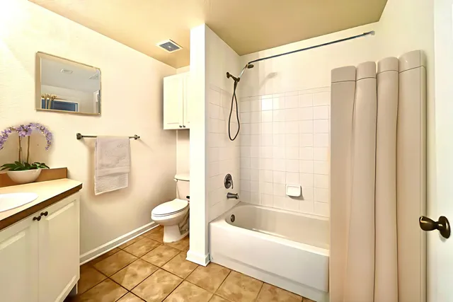 a bathroom with a granite countertop bathtub shower sink vanity and toilet