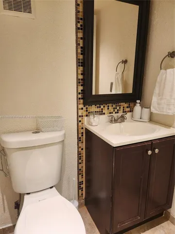 a bathroom with a sink vanity mirror and toilet