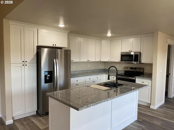a kitchen with granite countertop a refrigerator and a sink