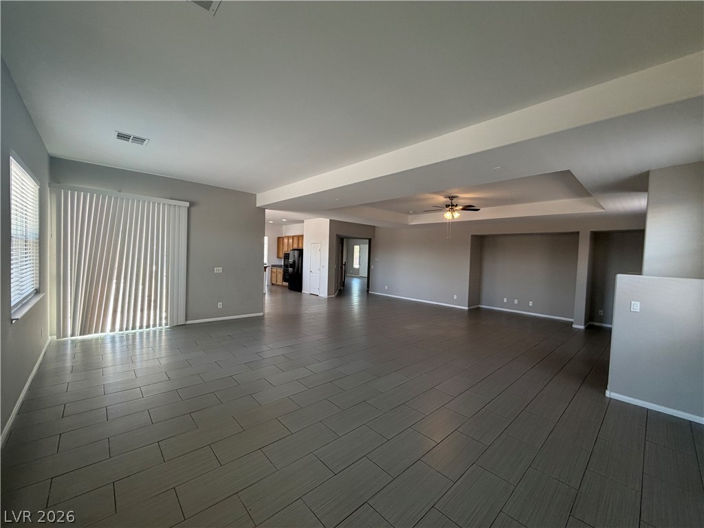 6116 Rabbit Track Street Las Vegas, NV 89130 - Photo 22 of 28 An airy living space with sleek tiled flooring and a tray ceiling, seamlessly flows into the kitchen.