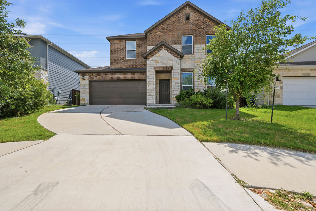 205 Stinchcomb Road Hutto, TX 78634 - Photo 1 of 1 A charming two-story home features a brick and stone facade, complemented by a neatly manicured lawn and an inviting concrete driveway.
