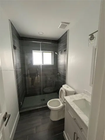 a bathroom with a granite countertop sink a toilet a mirror and shower