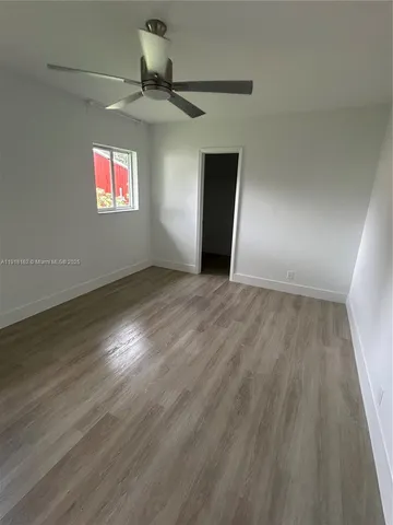 an empty room with wooden floor closet and windows