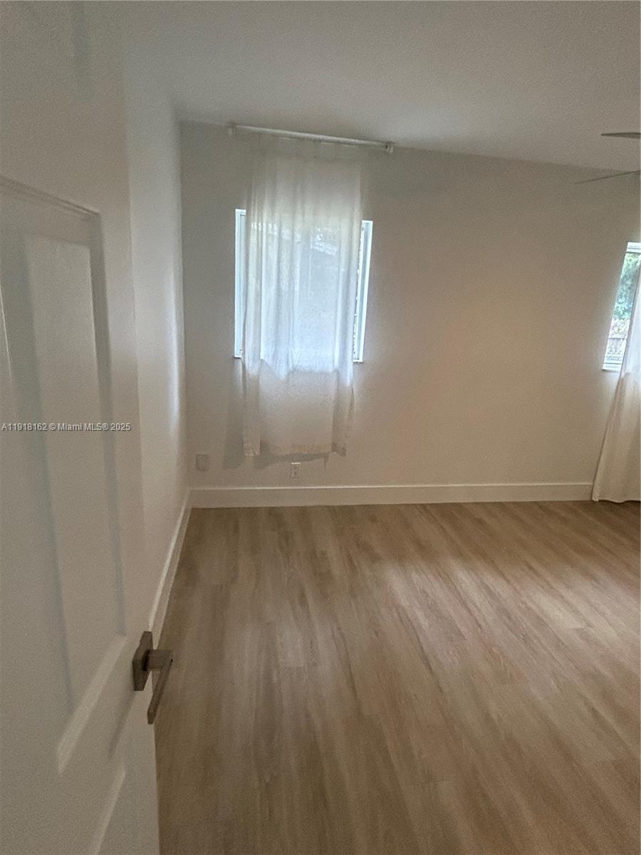 6121 Southwest 48th Court, Unit 3 Davie, FL 33314 - Photo 9 of 14 an empty room with wooden floor and windows