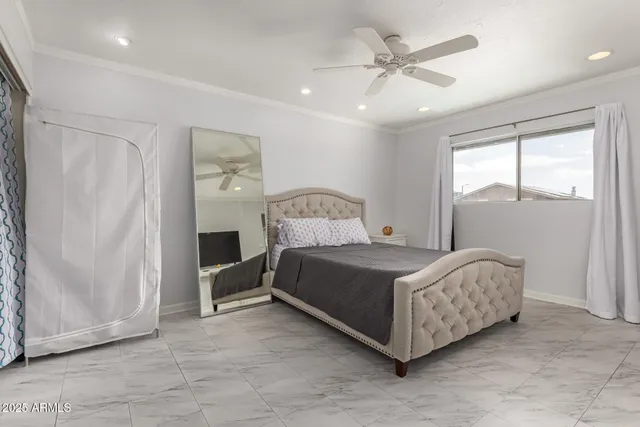 a bed sitting in a bedroom next to a window and a chandelier