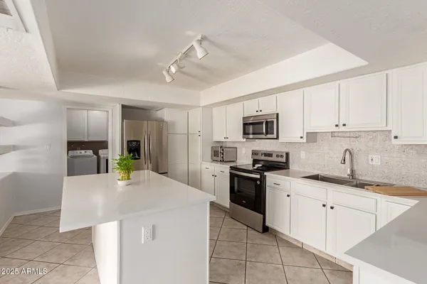a kitchen with stainless steel appliances granite countertop a sink dishwasher stove top oven and refrigerator with wooden cabinets