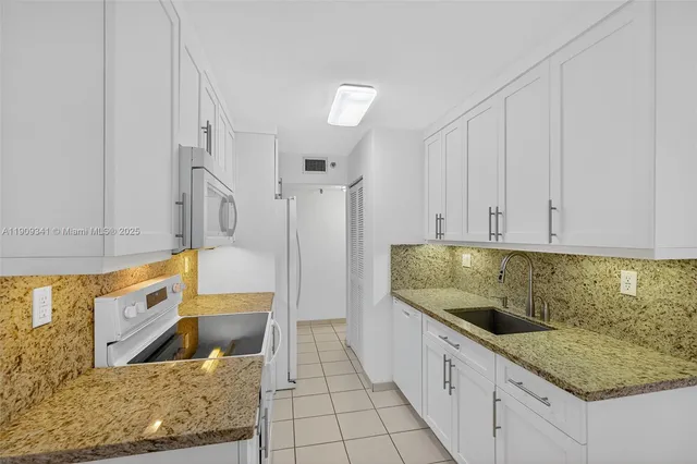 a kitchen with white cabinets and appliances