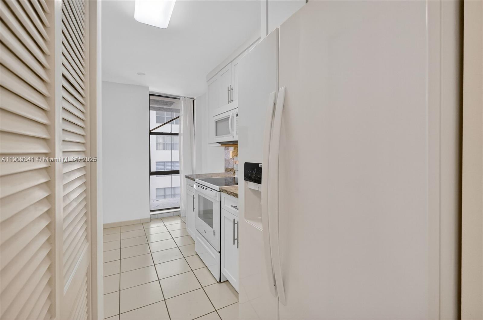 6061 Collins Avenue, Unit 7B Miami Beach, FL 33140 - Photo 24 of 41 a kitchen with white cabinets and appliances