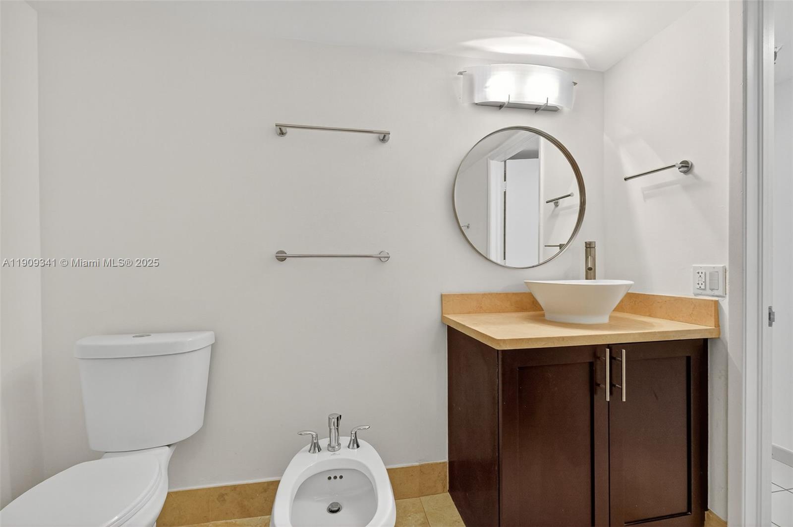 6061 Collins Avenue, Unit 7B Miami Beach, FL 33140 - Photo 39 of 41 a bathroom with a toilet a sink and a mirror