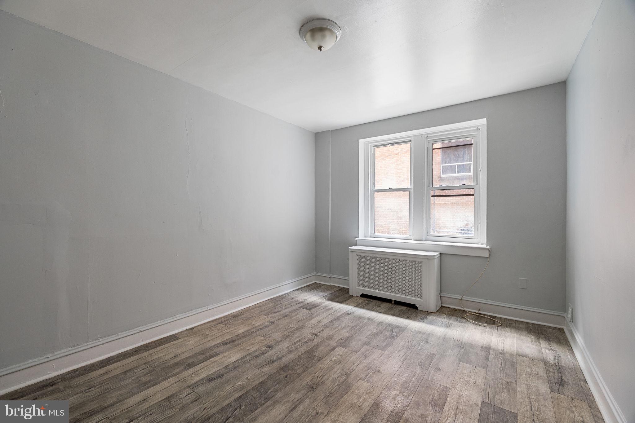 7250 Chestnut Street, Unit E101 Upper Darby, PA 19082 - Photo 13 of 18 an empty room with wooden floor and windows