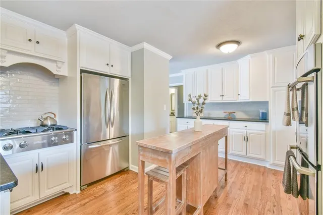 a kitchen with granite countertop a refrigerator a sink and white cabinets