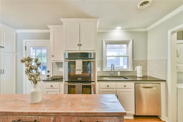 a kitchen with granite countertop a sink stainless steel appliances and white cabinets
