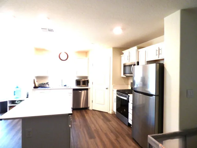 a kitchen with a refrigerator a stove top oven a counter space and wooden floor