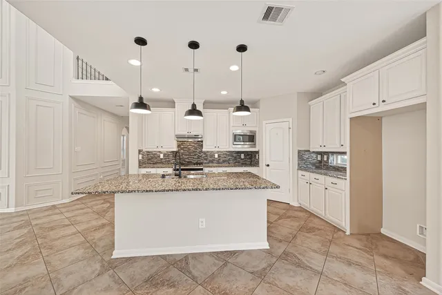 a large white kitchen with kitchen island a sink a stove and a refrigerator