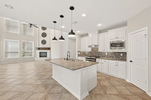 a kitchen with a stove a sink dishwasher a refrigerator and white cabinets with wooden floor