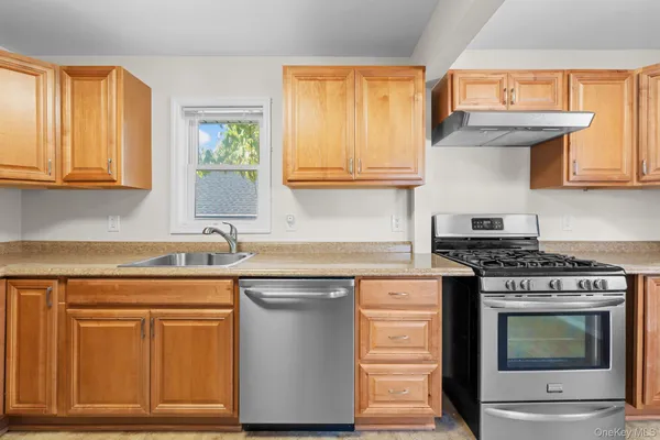 a kitchen with granite countertop a sink cabinets stainless steel appliances and a window
