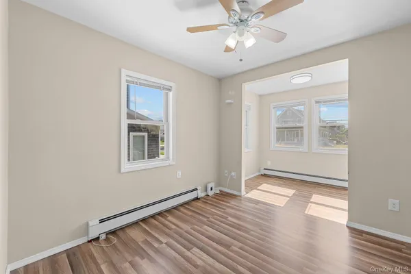 an empty room with wooden floor chandelier fan and windows