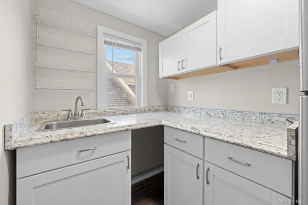 a kitchen with granite countertop white cabinets and a sink
