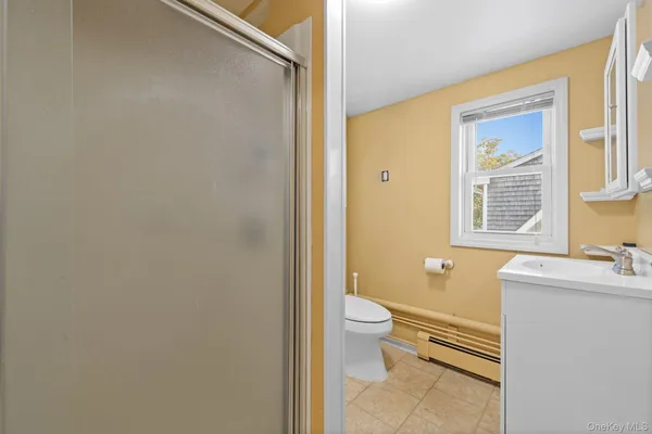 a bathroom with a sink mirror toilet and next to a window