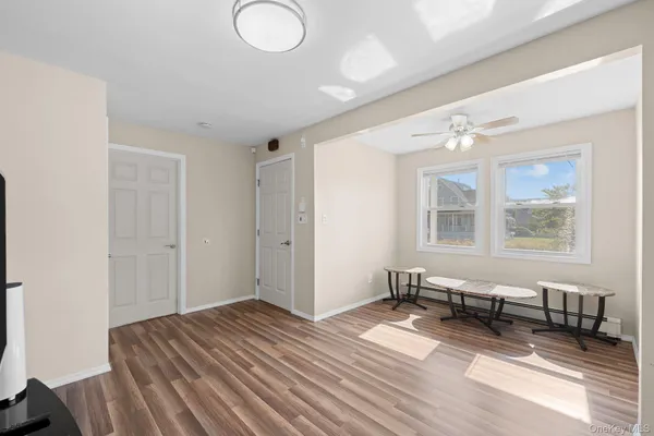 a view of empty room with wooden floor and fan