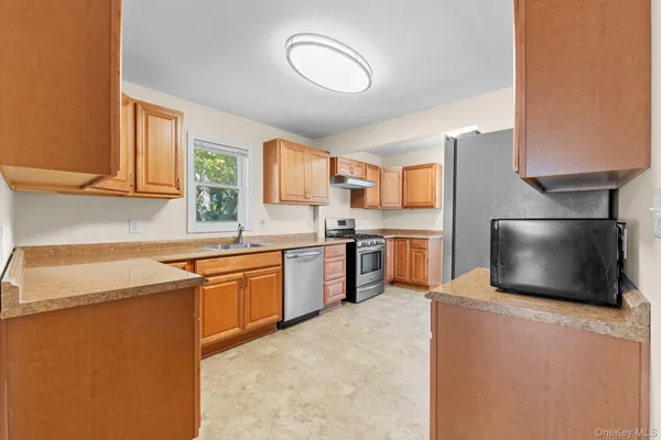 a kitchen with stainless steel appliances granite countertop a sink a stove a microwave a counter top space and cabinets