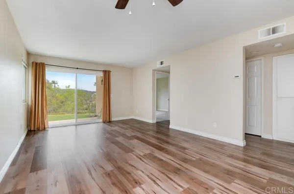 a view of an empty room with wooden floor and a window