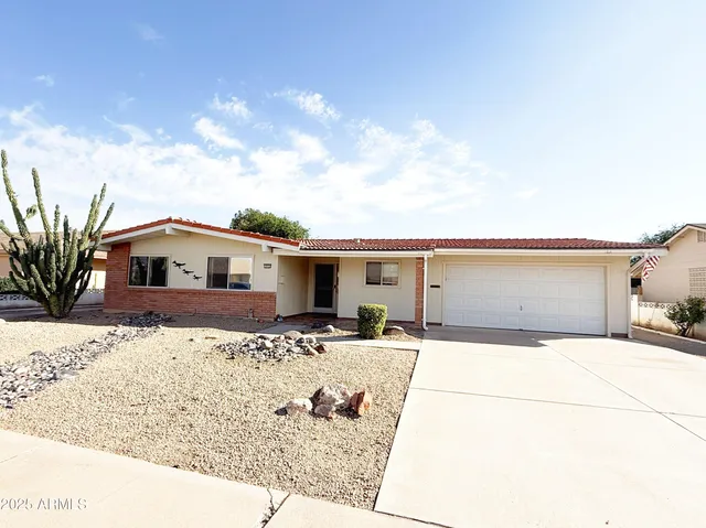 a front view of house with yard and trees in the background