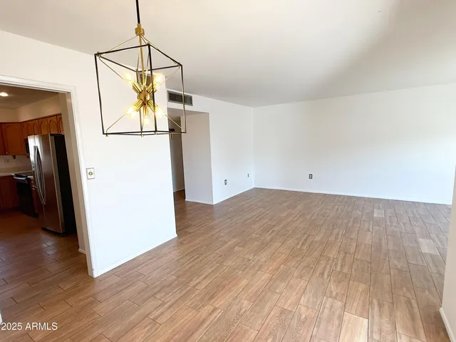 a view of a room with wooden floor and a refrigerator