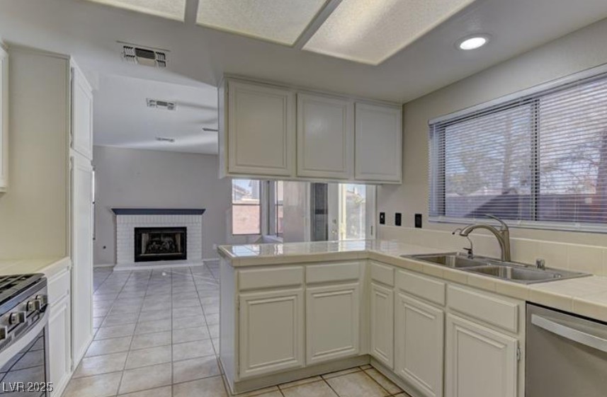 356 Amalfi Street Henderson, NV 89074 - Photo 15 of 15 Kitchen with tile counters, a brick fireplace, stainless steel appliances, light tile patterned flooring, and open floor plan