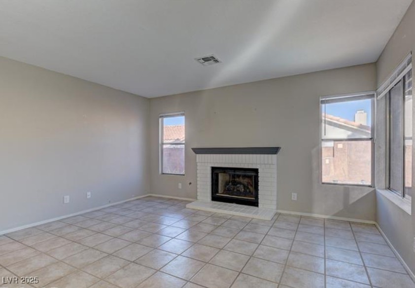356 Amalfi Street Henderson, NV 89074 - Photo 7 of 15 Unfurnished living room featuring light tile patterned floors, healthy amount of natural light, and a fireplace
