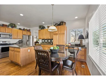 a kitchen with stainless steel appliances kitchen island granite countertop a table chairs and a refrigerator