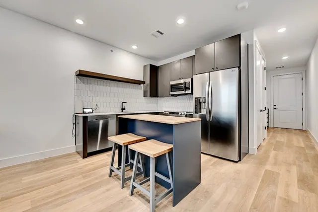 a kitchen with stainless steel appliances a refrigerator and a stove top oven