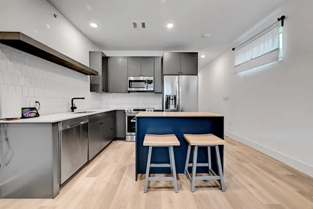 a kitchen with kitchen island stainless steel appliances cabinets a sink and a counter top space
