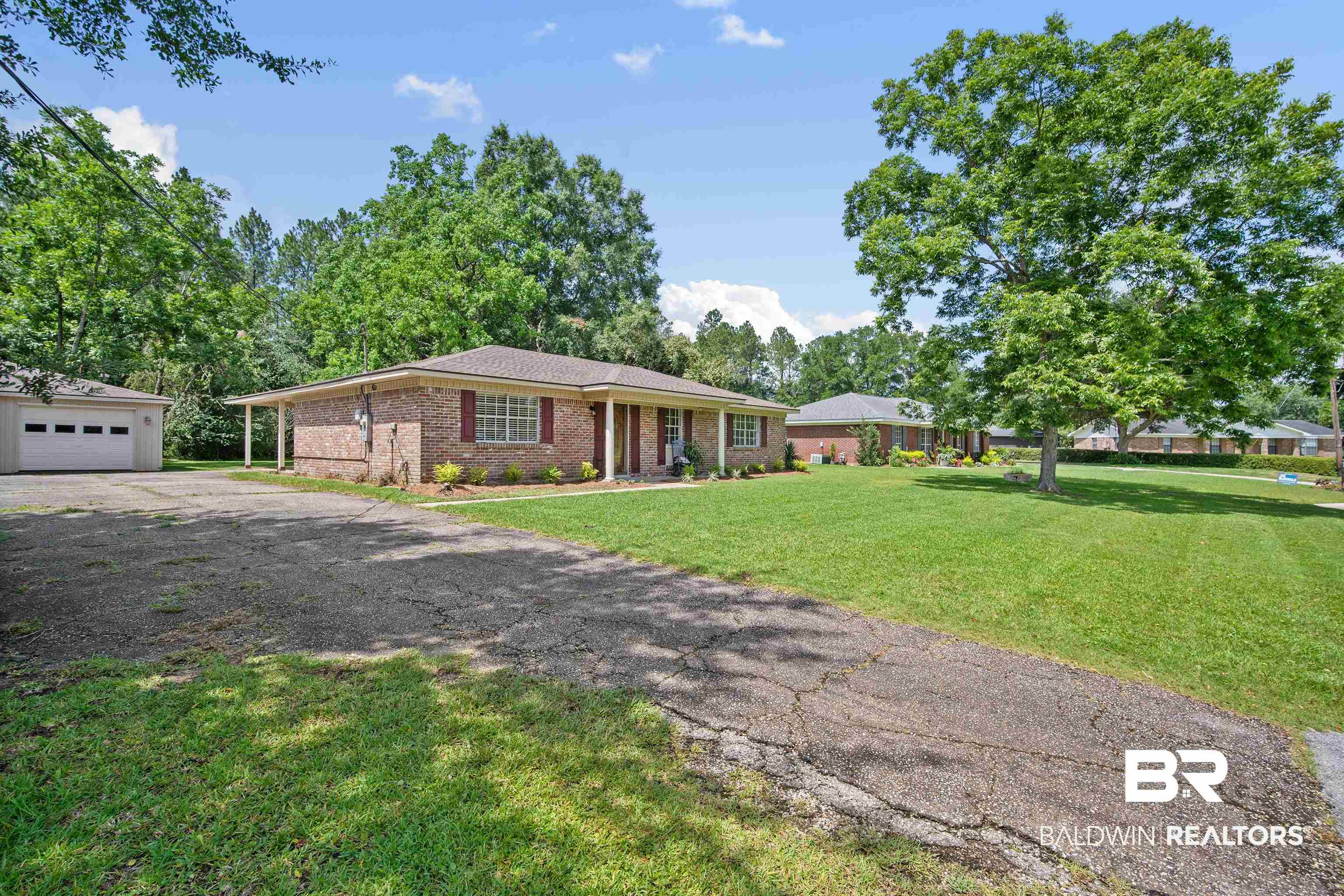 1325 Pawnee Circle Saraland, AL 36571 - Photo 2 of 26 Ranch-style house with brick siding, an outdoor structure, a front yard, asphalt driveway, and a detached garage