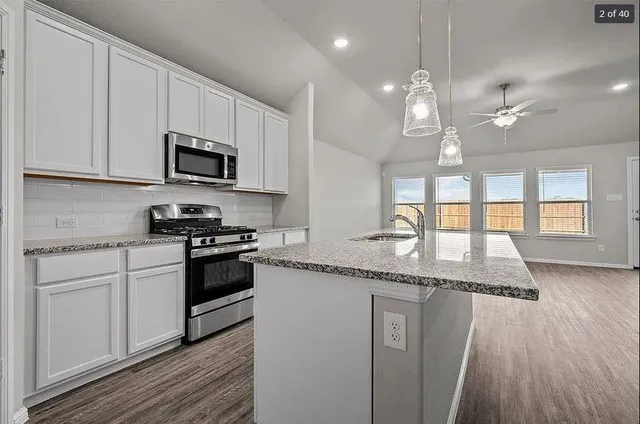 a kitchen with granite countertop a sink a counter space appliances and cabinets