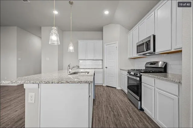 a kitchen with stainless steel appliances granite countertop a stove a sink and a microwave