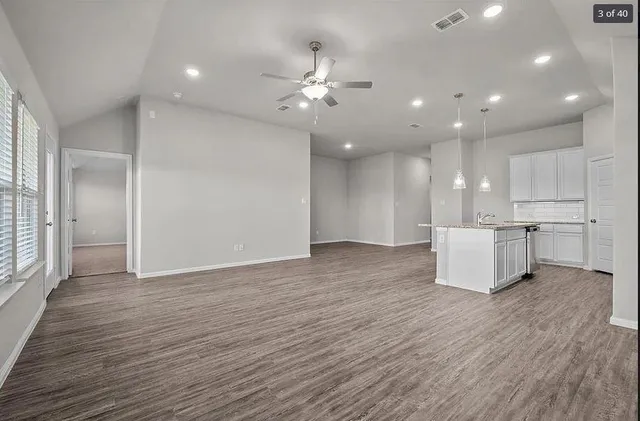 a view of a kitchen with kitchen island a sink wooden floor and a refrigerator