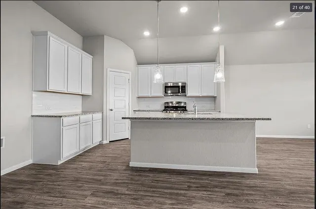 a kitchen with kitchen island a counter top space a sink stainless steel appliances and cabinets