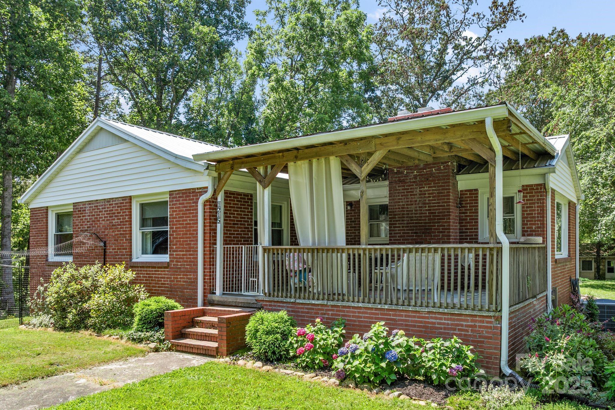 1215 Upper Brush Creek Road Fairview, NC 28730 - Photo 2 of 41 a view of a house with a small yard plants and large tree