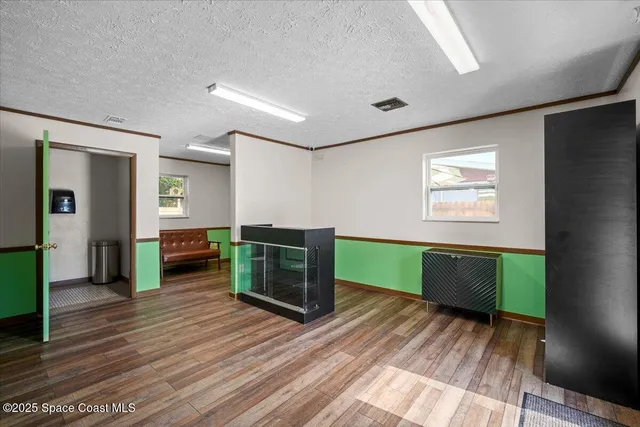 a view of an empty room with window and wooden floor