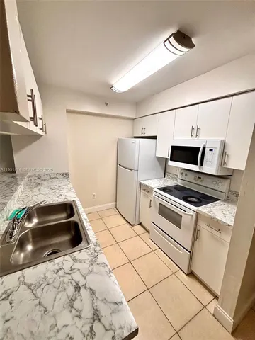 a view of a kitchen with a sink a stove top oven and cabinetry