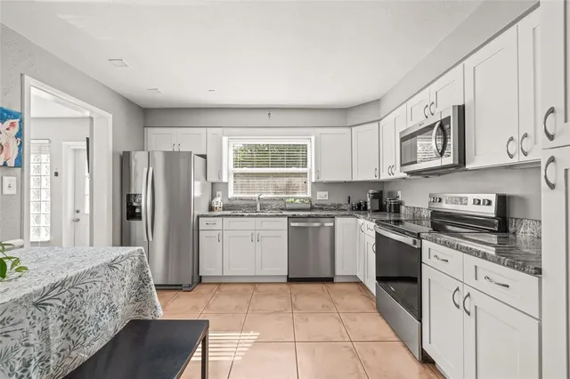 a kitchen with stainless steel appliances granite countertop a stove a sink a microwave a dining table and chairs with wooden floor