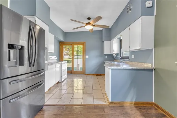 a kitchen with stainless steel appliances granite countertop a refrigerator a sink dishwasher a stove and white countertops with wooden floor