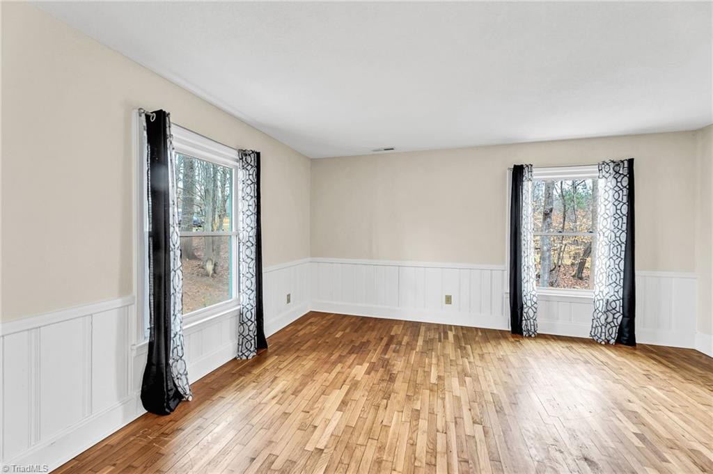 795 Dan Valley Road Madison, NC 27025 - Photo 17 of 38 Living Room: Features include nice hardwood flooring, a decorative chair rail to help protect the walls. wainscoting, 2 windows for natural lighting and fresh paint. Curtains stay with the home at closing.