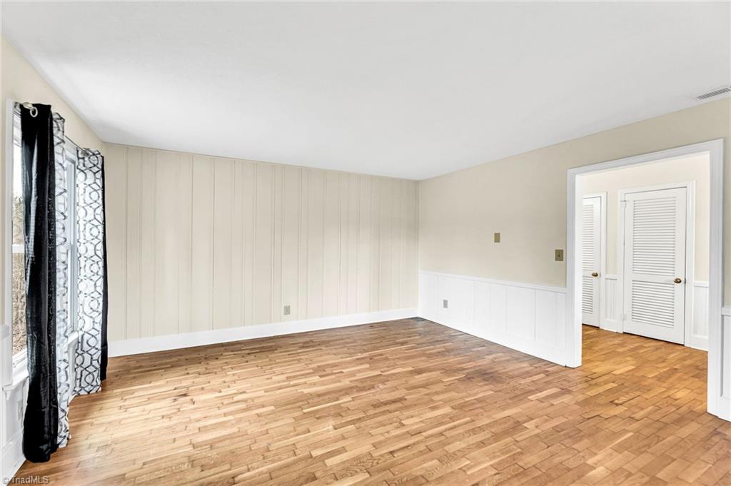 795 Dan Valley Road Madison, NC 27025 - Photo 2 of 38 Living Room: Features include nice hardwood flooring, a decorative chair rail to help protect the walls. wainscoting, 2 windows for natural lighting and fresh paint. The front entry way and foyer are shown through the open doorway.