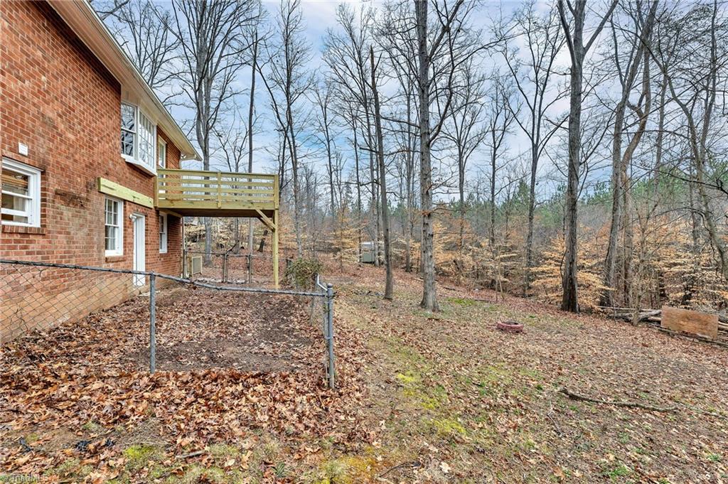 795 Dan Valley Road Madison, NC 27025 - Photo 36 of 38 Rear View looking from rear left to the right side: Here we can see the new rear deck, the dog run and the rear entry door into the basement den.